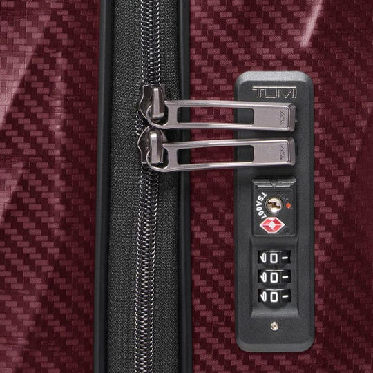 Close-up of a suitcase with a TSA-approved lock on a textured red background