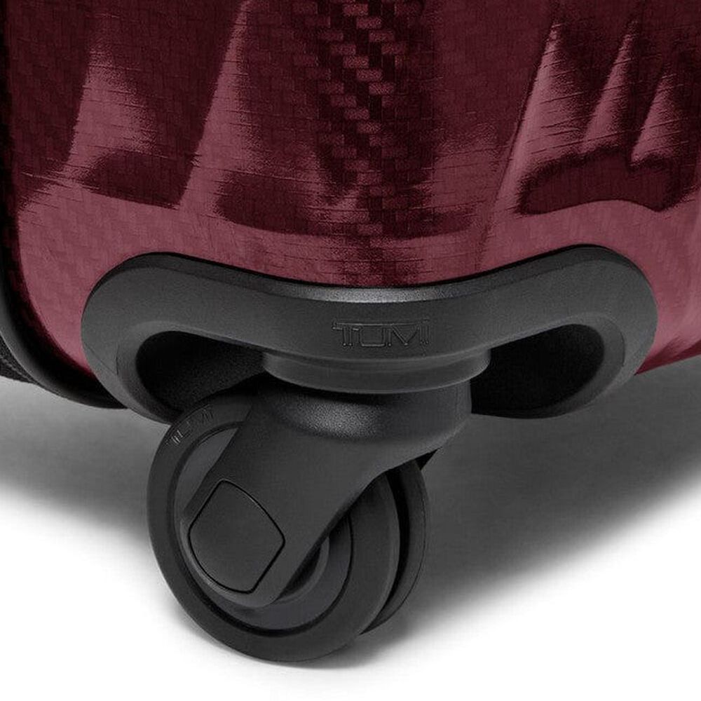 Close-up of a suitcase wheel on a red suitcase with 'TUMI' branding.