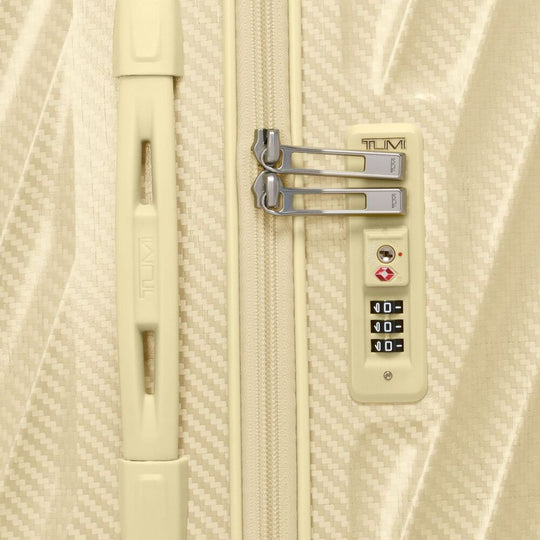 Beige suitcase with a combination lock on a textured beige background