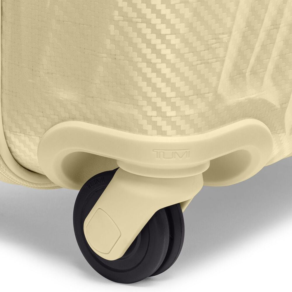 Close-up of a beige suitcase with a wheel on a light gray background