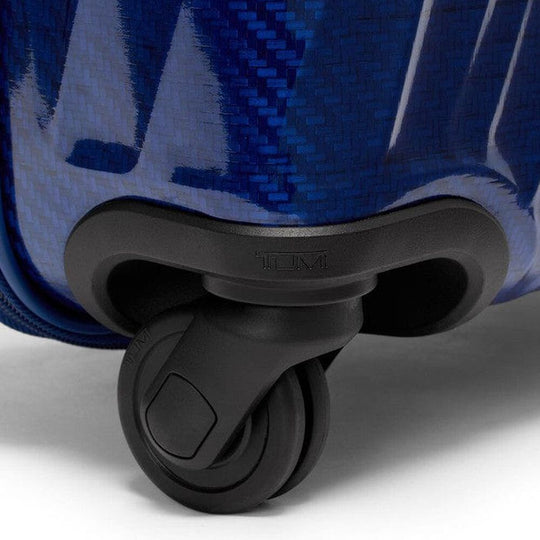 Close-up of a blue suitcase with a black wheel on a white background