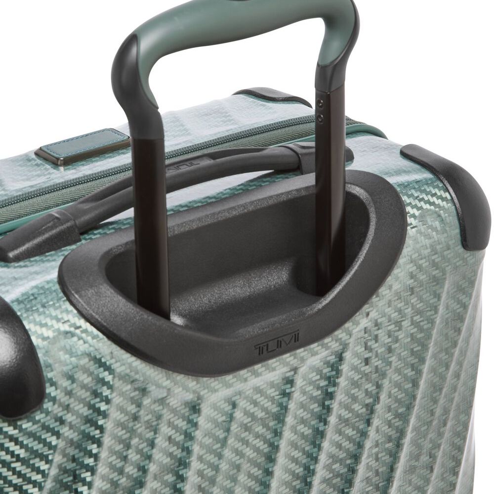 Close-up of a green suitcase handle on a textured surface