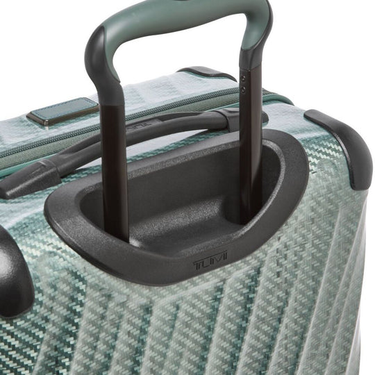 Close-up of a green suitcase handle on a textured surface
