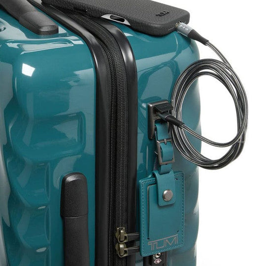 Teal suitcase with a black handle and security cable, featuring the TUMI brand.