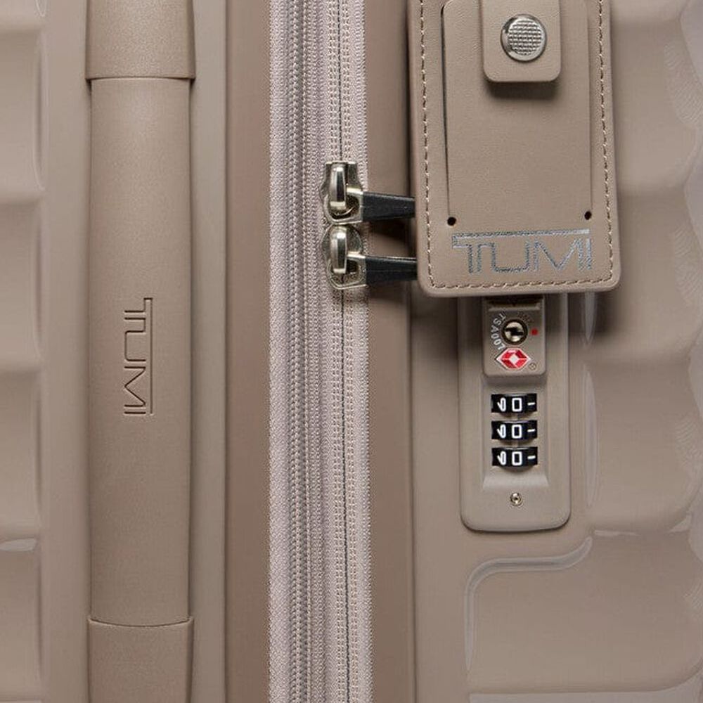 Close-up of a beige Tumi suitcase with a combination lock.