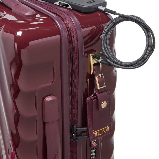 Maroon suitcase with a gold tag and black cable lock on a white background