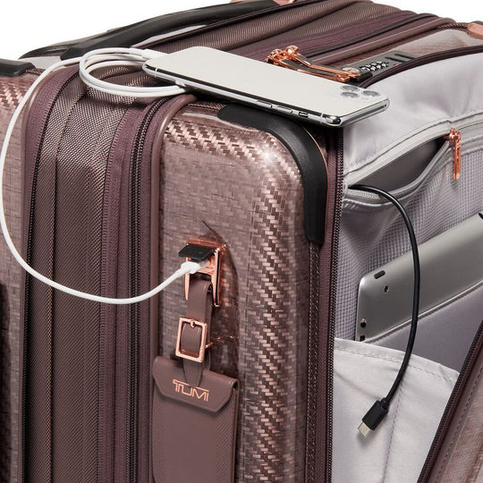 Brown suitcase with electronic devices and cables on top